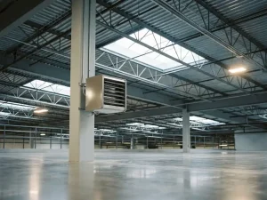 Industriële unit heater gemonteerd op een stalen kolom in een modern distributiecentrum met betonvloer en dakramen.